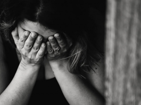 Black and white photo of woman wearing a wedding ring with her head in her hands