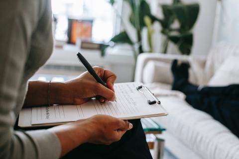 a person sitting writing notes on a clipboard