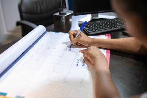 person writing in planner at desk