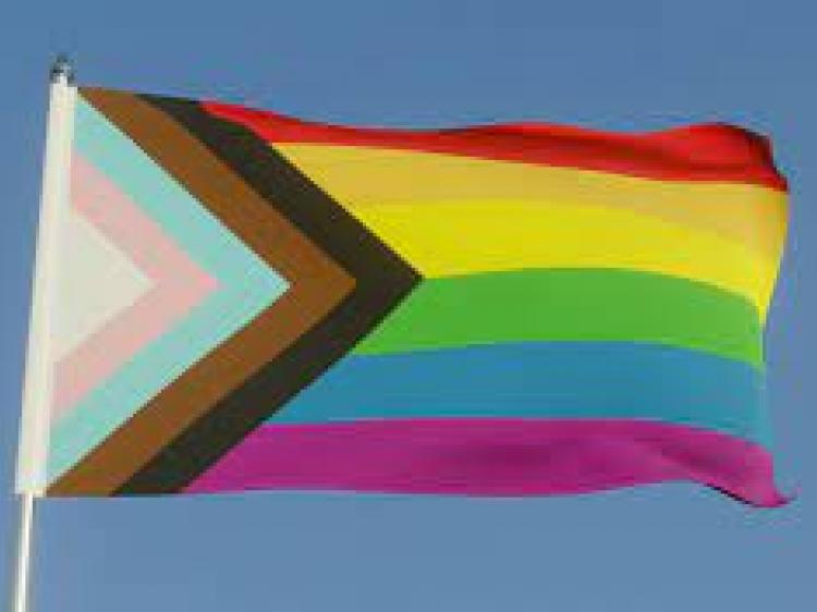 LGBTQ+ Flag against a blue sky 