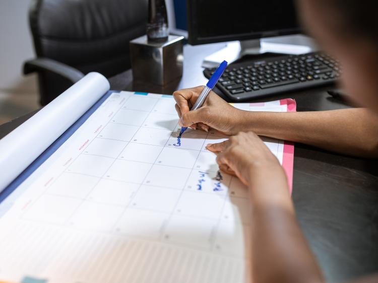 person writing in planner at desk